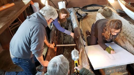 Tim Spahr with excavation team studying the remains of the dugout canoe.